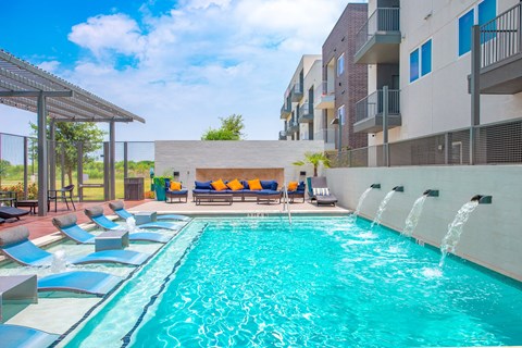 a swimming pool with a waterfall in front of an apartment building